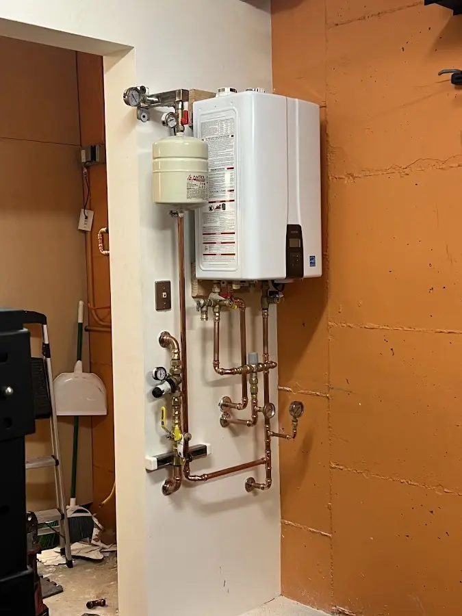 Plumbing technician inspecting water heater connections in Clifton